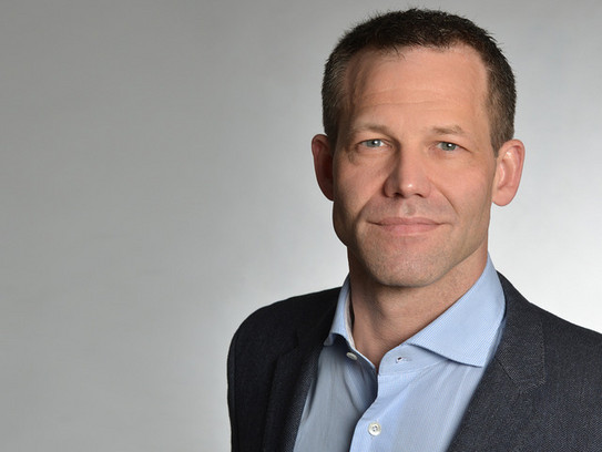 Junger dynamischer Physiker, der freundlich in die Kamera schaut.